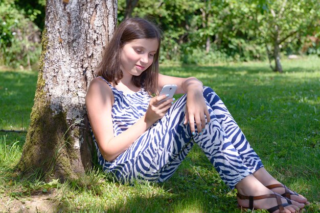 Pré adolescente texto sur téléphone mobile