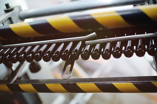 Des préformes noires pour le soufflage de bouteilles PET en plastique se déplacent sur un tapis roulant dans le contexte de l'usine.