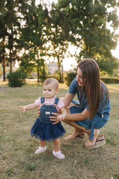 Première étape de l'adorable petite fille dans le parc d'été Maman et sa fille marchant