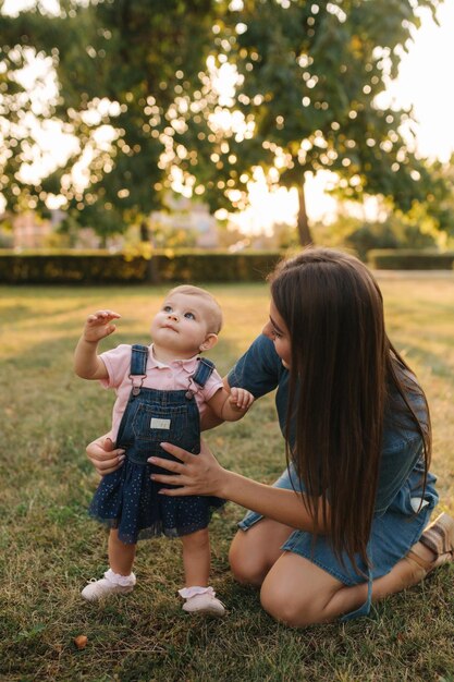 Première étape de l'adorable petite fille dans le parc d'été Maman et sa fille marchant