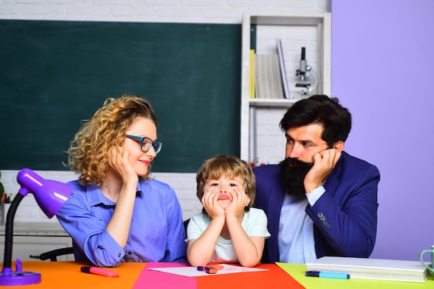 La première fois à l'école, maman et papa aident un enfant garçon famille heureuse parentalité famille heureuse scolarisation mathématiques