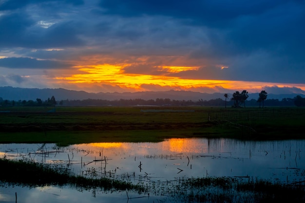 La première lumière dorée du matin du soleil jetant un coup d'œil à travers les gros nuages de pluie Le premier soleil éclaire le paysage La lumière du soleil et les nuages