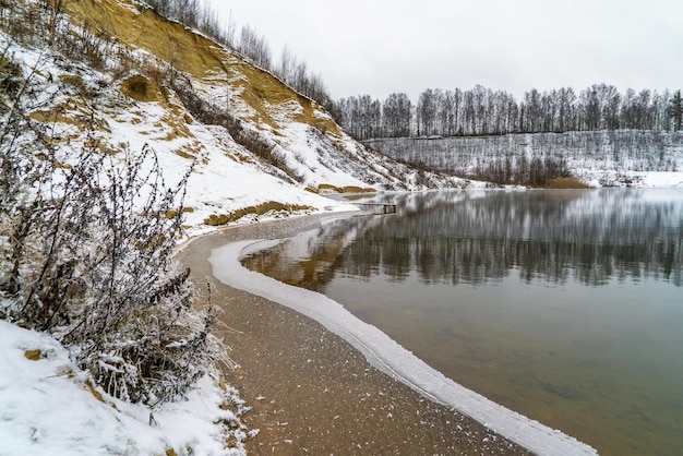 La première neige et le premier bord de glace sur l'étang au petit matin glacial