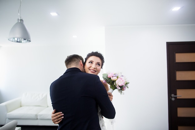 La première réunion. Le marié entre dans la chambre à la mariée avec un bouquet.