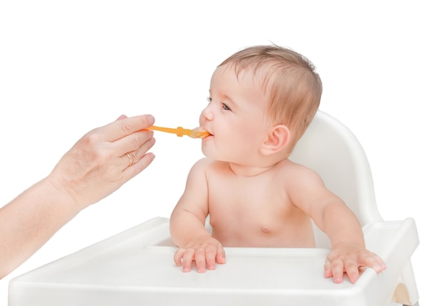 La première tétée du bébé. La main tend une cuillère avec de la purée de pommes de terre à un enfant