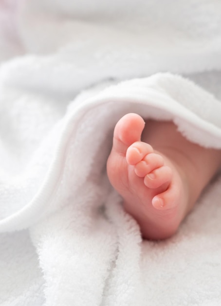 Les premiers pas du bébé : le petit pied dévoilé à partir d’une serviette blanche