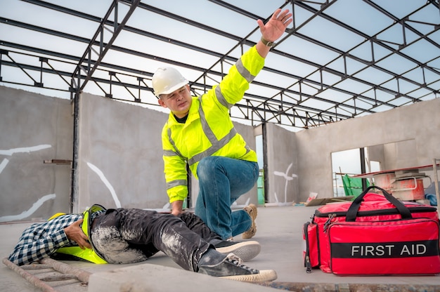 Premiers secours pour les accidents d'urgence sur les chantiers de construction. Un ouvrier du bâtiment a été blessé lors d'une chute de hauteur sur un chantier de construction. Les ingénieurs aident les premiers secours, l'équipe de sécurité aide les employés en cas d'accident.