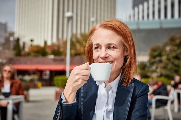 Prenant un moment pour se ressourcer, une femme d'affaires d'âge moyen prospère profite d'une pause-café paisible