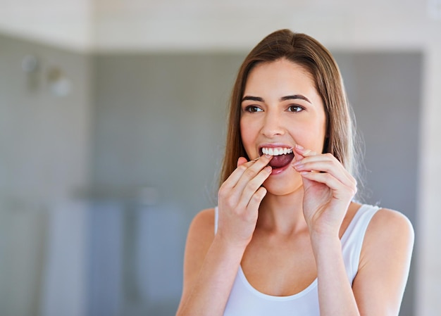 Prendre bien soin de ses dents Photo recadrée d'une belle jeune femme passant la soie dentaire