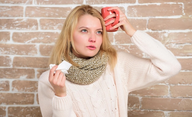 Prendre une cure. Une femme mignonne a attrapé un terrible virus du rhume. Femme malade avec mal de gorge buvant une tasse de thé chaud. Jolie fille avec un rhume nasal souffrant de maux de tête. Symptômes du rhume et de la grippe.