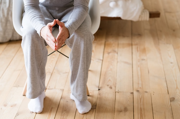 Prendre une décision. Homme en pyjama assis dans une chaise blanche avec des mains de clochers.