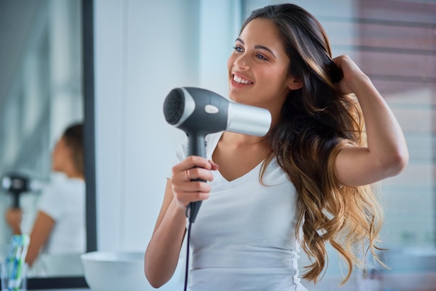 Prendre grand soin de ses cheveux Photo d'une jolie jeune femme se séchant les cheveux dans la salle de bain