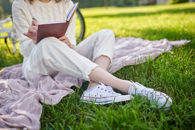 Prendre des notes. Une jeune fille avec un journal en mains pensant et prenant des notes