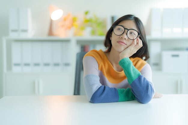 Prendre une pause dans ses études à la bibliothèque est une jeune femme souriante ou une étudiante portant des lunettes