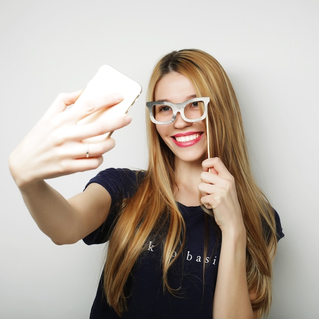 Prendre une photo. Femme aux cheveux blonds gaie souriante faisant selfie