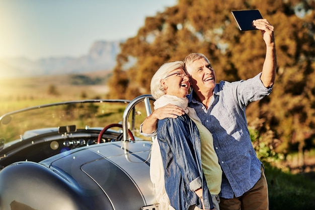 Prendre un selfie pour les petits-enfants Photo d'un couple âgé posant pour un selfie lors d'un roadtrip dans une décapotable