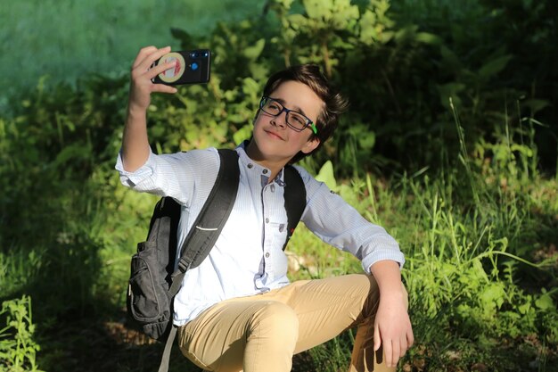 Prendre des selfies au milieu de la forêt avec la couleur du soleil sur le fond d'été du visage