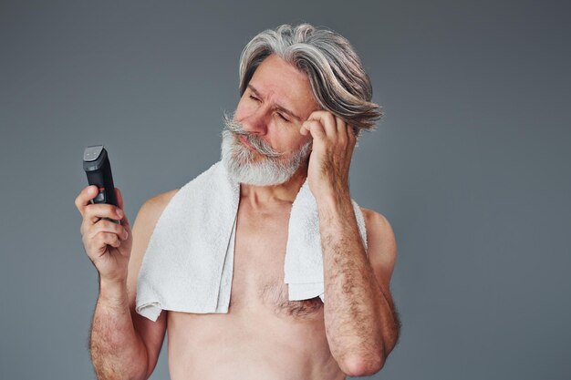 Prendre soin de la barbe Un homme âgé moderne et élégant aux cheveux gris est à l'intérieur