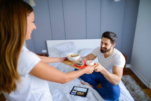 Prendre soin de jolie fille apportant son petit-déjeuner copain au lit. Objectifs de couple.