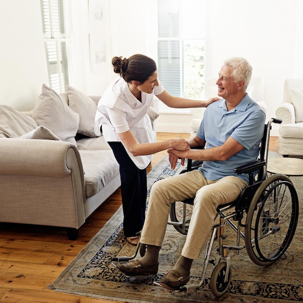 Prendre soin des personnes âgées est sa vocation Photo d'un soignant aidant un homme âgé en fauteuil roulant à la maison