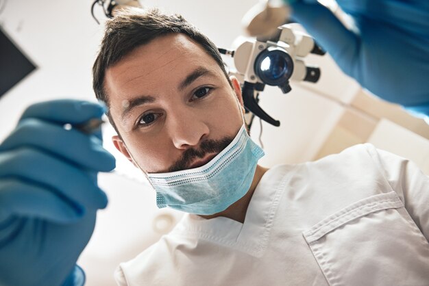 Prendre soin de vous votre sourire jeune dentiste masculin regarde les dents sur la bouche ouverte des patients