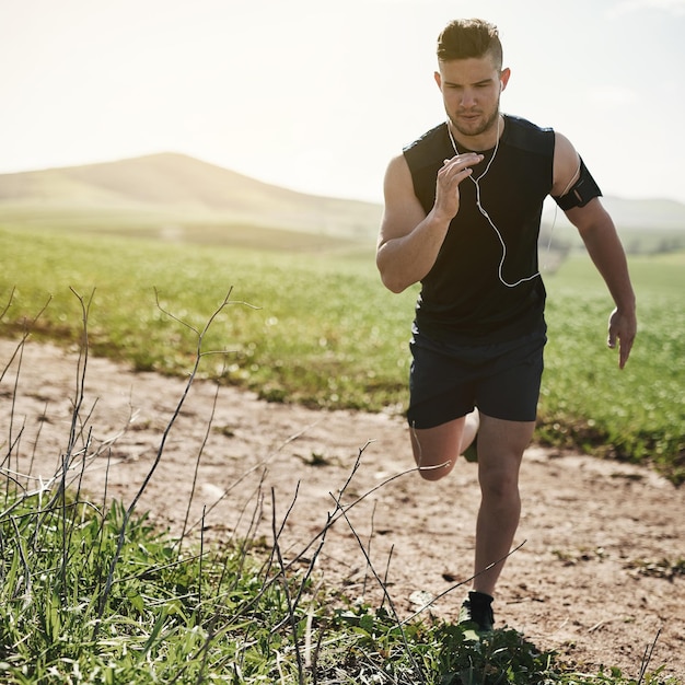 Photo prendre son entraînement hors route photo pleine longueur d'un beau jeune homme courant à l'extérieur