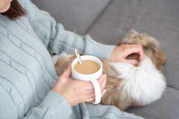 Prendre une tasse de café chaud sur le canapé avec votre chien