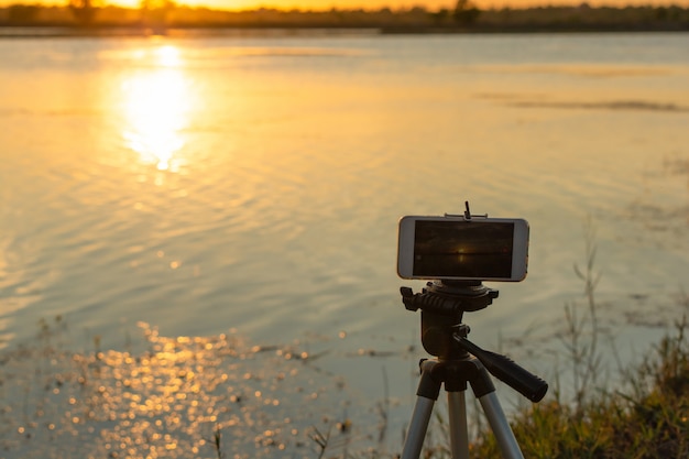 Prenez des photos du coucher du soleil sur la rivière avec un smartphone sur un trépied