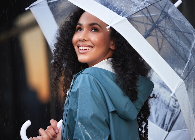 Photo prenez une seconde pour admirer la beauté qu'est la pluie. plan d'une jeune femme admirant la pluie dans la ville.