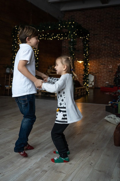 Préparatifs de vacances. Deux enfants profitent de nombreux cadeaux de Noël à la maison. Hiver froid, temps de neige.