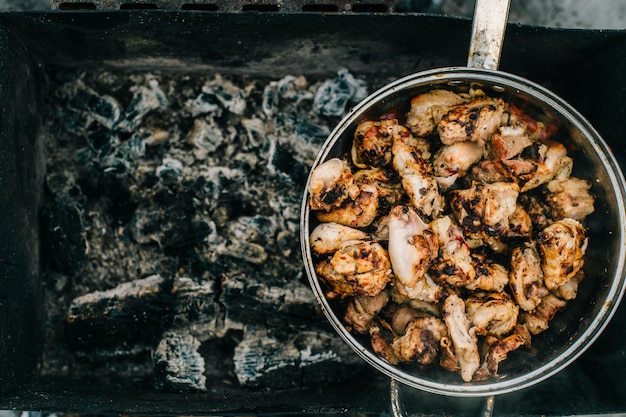 Préparation sur barbecue. Plat avec de la viande rôtie sur fond abstrait. Repas barbecue savoureux et chaud au charbon et au bois de chauffage brûlé. Cuisson au feu en plein air. Bonne odeur de nourriture. Morceaux de poulet frit