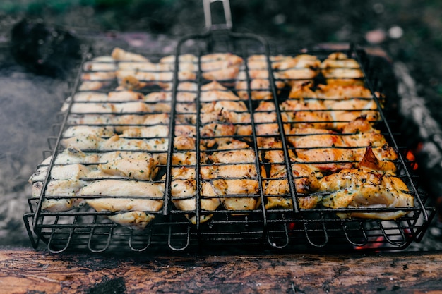 Préparation Sur Barbecue. Plat Avec Viande Rôtie Sur Herbe Floue. Repas Barbecue Savoureux Et Chaud Au Charbon Et Au Bois De Chauffage Brûlé. Cuisson Au Feu En Plein Air.