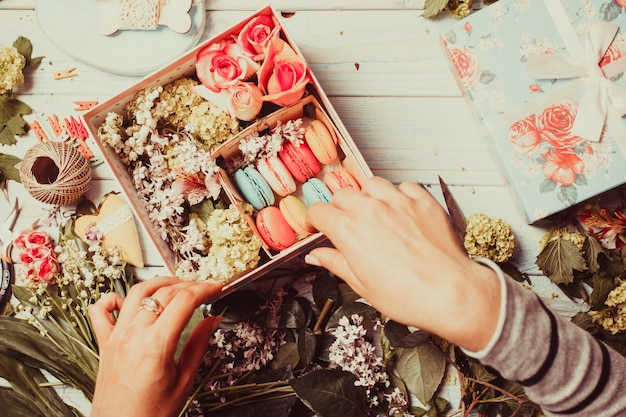 Préparation d'une boîte à fleurs avec des macarons, vue de dessus du lieu de travail du fleuriste