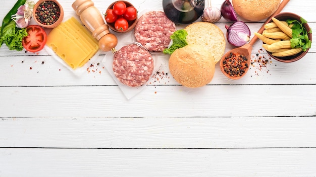 Préparation de burger Viande tomates oignons Sur un fond en bois blanc Vue de dessus Espace de copie gratuit