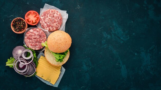 Préparation de burger Viande tomates oignons Sur fond de pierre noire Vue de dessus Espace de copie gratuit