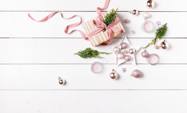 Préparation des cadeaux de Noël sur une table en bois blanche avec des décorations roses. Mise à plat, vue de dessus, espace de copie, bannière