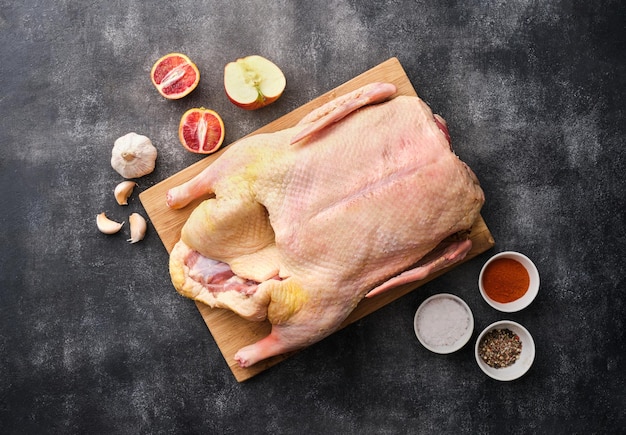 Préparation Canard ou oie entier cru Canard aux pommes et épices sur une planche de bois