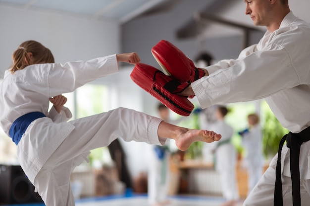 Préparation à la compétition. Fille portant un kimono blanc se préparant à la compétition avec un entraîneur