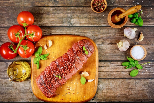 Préparation du bœuf pour le gril avec des épices et des tomates. Vue de dessus.