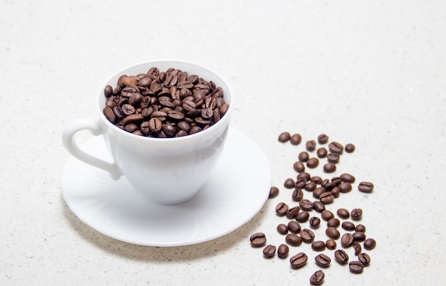 Préparation du café. Grains de café dans une tasse blanche. Sur fond clair