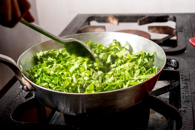 Préparation du chou frisé dans une poêle à frire sur la cuisinière.