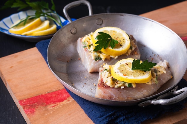 Photo préparation du concept d'aliments sains pour le beurre d'ail au citron fait maison morue cuite au four sur fond noir avec espace de copie