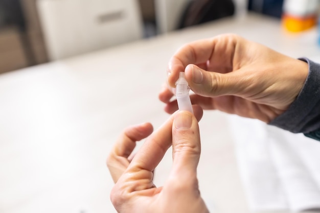 Préparation du liquide à appliquer. Une jeune femme faisant le test rapide d'antigène chez elle, sras-cov-2, coronavirus, covid-19