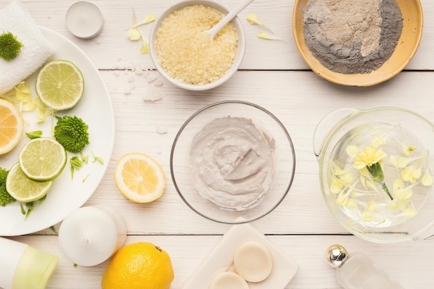 Préparation du masque de boue cosmétique dans un bol en verre sur fond blanc. Vue de dessus de l'émulsion d'argile pour le visage sur table avec des produits de spa. Cosmétiques naturels pour le traitement à domicile ou en salon