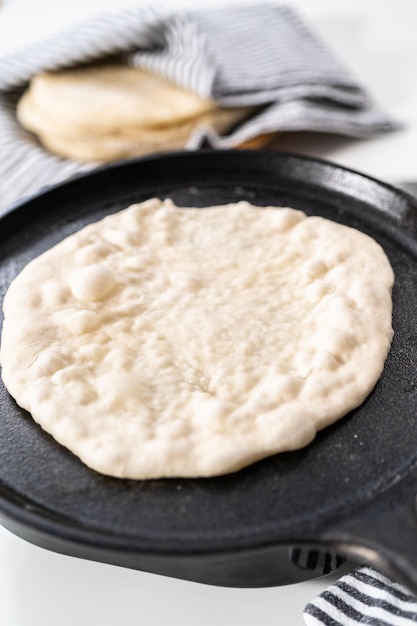 Préparation du pain plat fait maison sur une poêle en fonte.