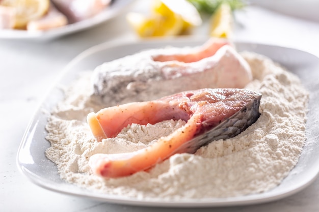 Préparation du poisson frais avant la friture en l'enveloppant dans la farine.