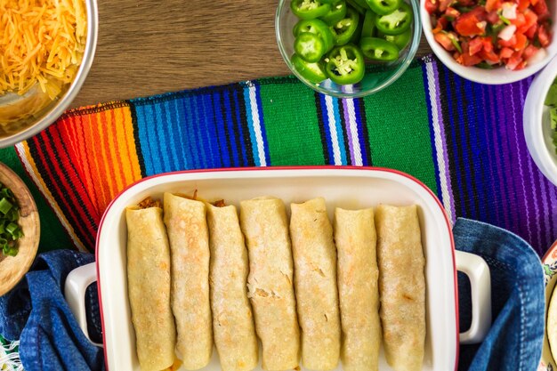 Préparation d'enchiladas au poulet avec du cheddar et de la sauce.