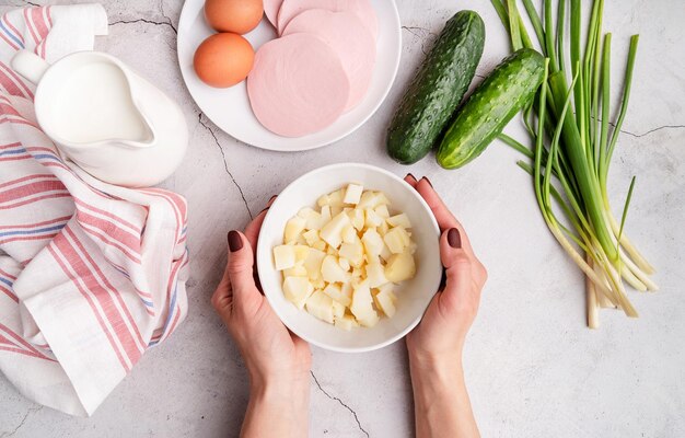 Préparation étape par étape de la soupe d'okroshka froide avec des saucisses étape 2 pommes de terre bouillies hachées dans un bol vue supérieure