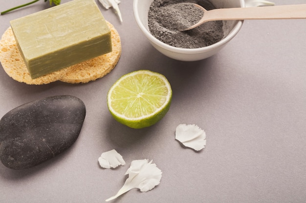 Préparation d'un masque cosmétique de boue noire sur fond gris avec divers produits de soin de la peau. Poudre d'argile pour le visage sèche dans un bol. Cosmétiques naturels pour les soins spa à domicile ou en salon