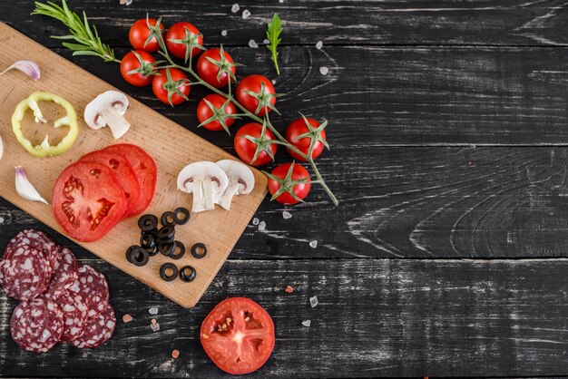 Préparation de la pâte et des légumes à la production de pizza. Ingrédients pour la production de pizza sur un fond en bois